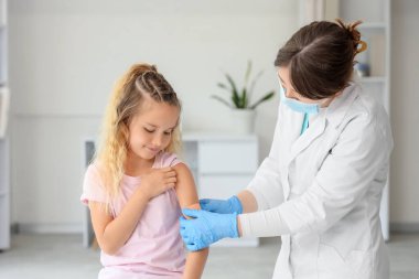 Klinikte aşıdan sonra doktordan yama alan tatlı küçük kız.