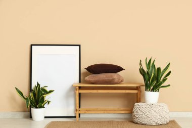 Yastıklı bank, Sansevieria bitkileri ve odada bej duvarın yanındaki boş çerçeve.