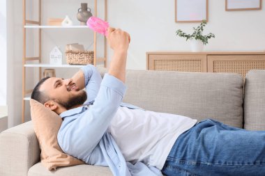 Evdeki kanepede vantilatörlü genç bir adam yatıyor.