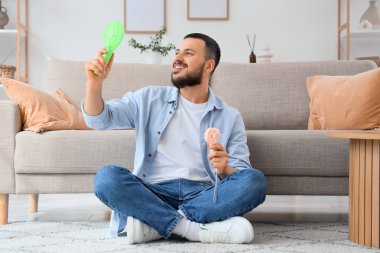 Evde mini hayranları olan genç bir adam var.