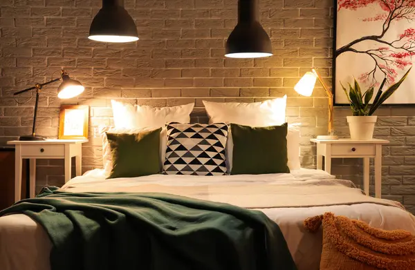 Rahat yatağın üzerinde battaniyeler ve gece lambaları olan modern yatak odasının içi.