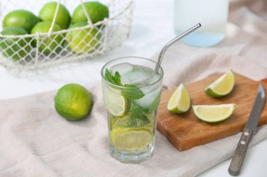 Beyaz arka planda limonlu ve naneli taze mojito kokteyli.
