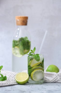 Cam ve bir şişe taze Mojito kokteyli. Gri arka planda naneli.