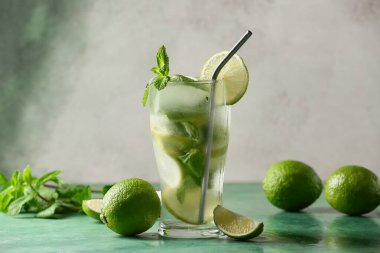 Yeşil masada limonlu ve naneli bir bardak taze mojito kokteyli.