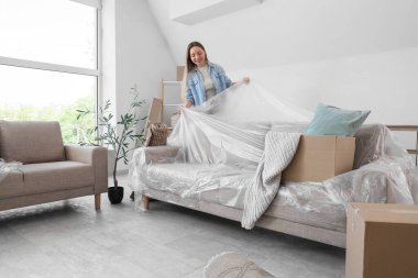 Taşındığı gün kanepeyi filmle kaplayan genç bir kadın.