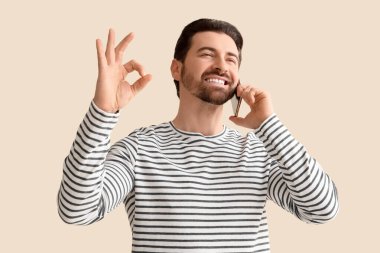 Genç adam cep telefonuyla konuşuyor ve arka planda iyi görünüyor.