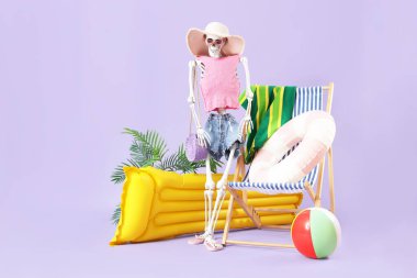 Leylak arka planında plaj aksesuarları olan insan iskeleti. Yaz tatili kavramı