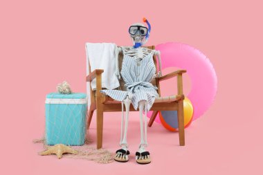 Sandalyede insan iskeleti ve pembe arka planda plaj aksesuarları. Yaz tatili kavramı