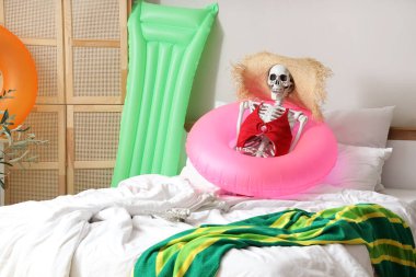 Yatak odasında yüzme yüzüğü olan insan iskeleti. Yaz tatili kavramı