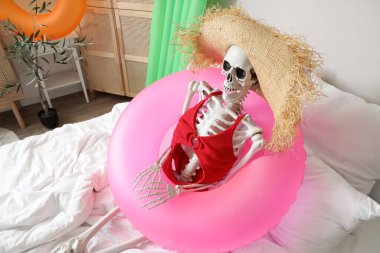 Yatak odasında yüzme yüzüğü olan insan iskeleti. Yaz tatili kavramı