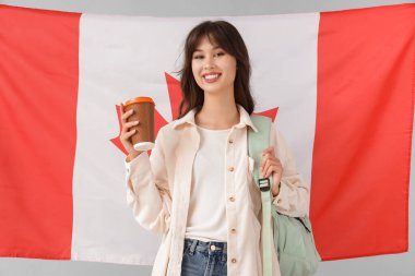 Kanada bayrağına karşı açık arkaplanda kahve fincanı taşıyan bayan öğrenci