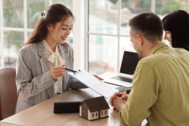 Asyalı kadın emlakçı ofiste çifte ev satıyor.