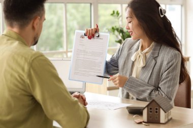 Asyalı kadın emlakçı ofiste çiftlere anlaşma gösteriyor.