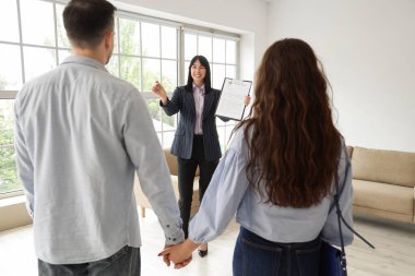 Kadın emlakçı odada çifte ev satıyor.