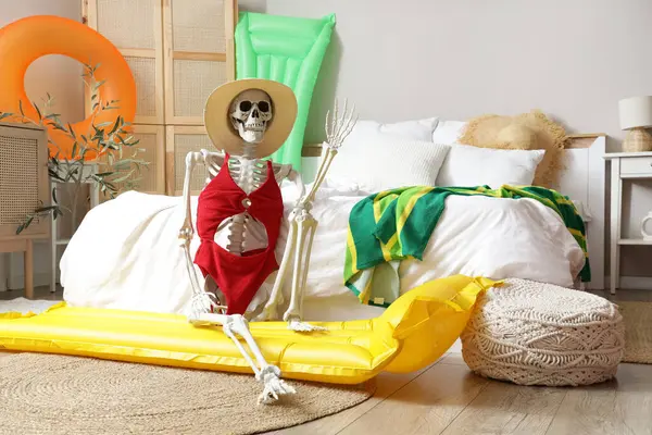 Yatak odasında plaj aksesuarları olan insan iskeleti. Yaz tatili kavramı