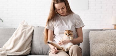 Evdeki kanepede oturan sevimli kedili genç kadın.