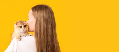 Sarı arka planda genç bir kadın ve sevimli bir kedi. Mesaj için yeri var.