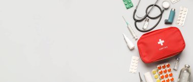 İlk yardım çantası ve gri arka planda haplar.