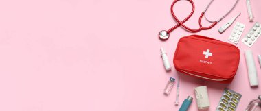 İlk yardım çantası ve pembe arka planda haplar.