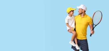 Küçük çocuk ve tenis raketi olan antrenörü açık mavi arka planda ve mesaj için yeri var.