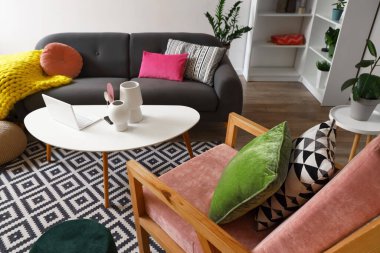 Gri kanepesi, koltuğu ve kahve masasının üzerinde modern dizüstü bilgisayarı olan şık bir oturma odası.