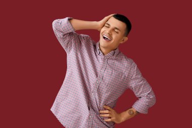 Kırmızı arka planda gülen mutlu genç adamın portresi