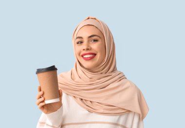 Mavi arka planda bir fincan kahvesi olan güzel Müslüman kadın.