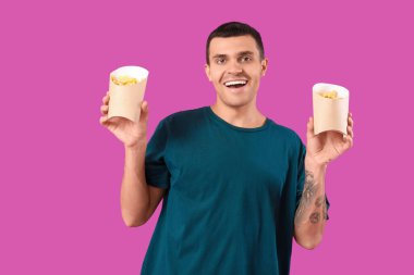 Mor arka planda patates kızartması olan mutlu genç adam.