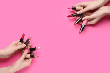 Pembe arka planda bir sürü ruju olan kadın elleri.