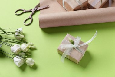 Yeşil arkaplanlı hediye kutuları, makas ve güller. Kadınlar Günü kutlaması