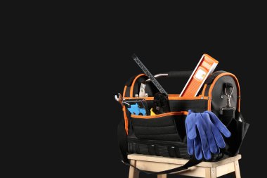 Siyah arkaplanda elektrikli alet çantası olan merdiven, yakın plan