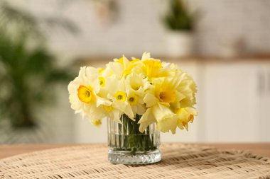 Cam vazoda güzel bir buket nergis ve masada hasır, yakın plan.