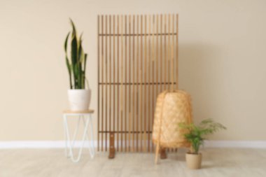 Kahve sehpası, ev bitkisi, rattan sepeti ve katlanır ekranı olan güzel bir oda.