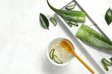 Bir kase aloe vera jeli ve beyaz arkaplanda yapraklar