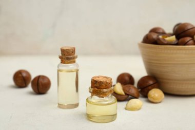 Bir şişe macadamia yağı ve fındıklı kase, yakın plan.