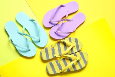 Sarı arka planda farklı tarz parmak arası terlikler.