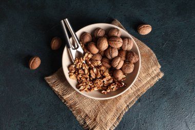 Koyu arkaplanda ceviz ve fındık kıracağı olan bir kase.