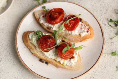 Beyaz zemin üzerinde ricotta ve mikro yeşil ile lezzetli domates bruschetta tabağı