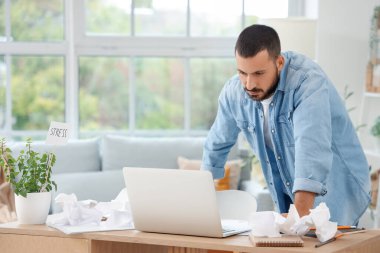 Stresli genç adam evde çalışıyor.