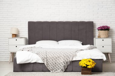 Yatak odasının içinde masalar ve kasımpatı çiçekleri var.