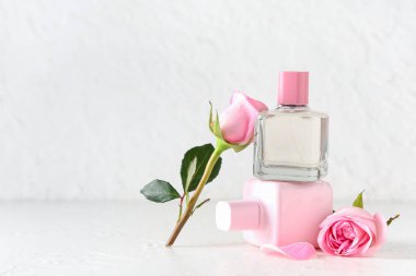 Parfüm şişeleri ve beyaz arka planda güzel pembe güller.