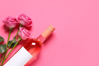 Bir şişe pembe şarap ve arka planda güzel güller.