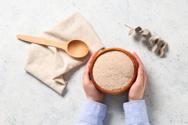 Kadın eli ve kasesinde hafif arka planda psyllium kabuğu tozu var.