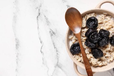 Kuru erik, süt ve mermer zemin üzerinde ahşap kaşık ile lezzetli yulaf ezmesi