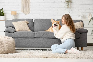 Oturma odasında Corgi köpeği olan güzel genç bir kadın.