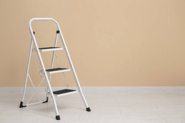 Bej duvarın yanındaki bakım merdiveni.