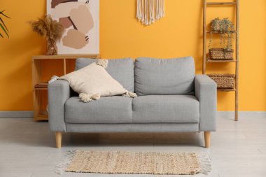 Gri kanepeli, sehpalı ve ahşap merdivenli ev bitkilerli şık bir oda.