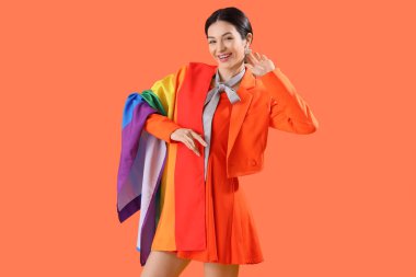 Turuncu arka planda gökkuşağı bayrağı olan güzel genç bir kadın. LGBT kavramı