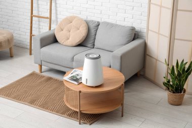 Masasında hava nemlendirici ve kanepe olan bir oturma odası.