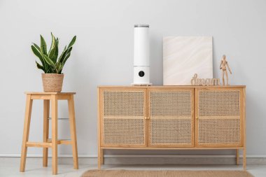 Oda odasındaki ışık duvarının yanındaki çekmecelerde boya ve dekor içeren hava nemlendirici.